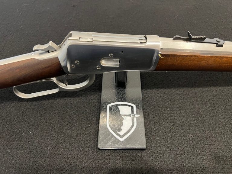 Eine Gewehr mit Holzschaft auf einem Ständer mit Logo.